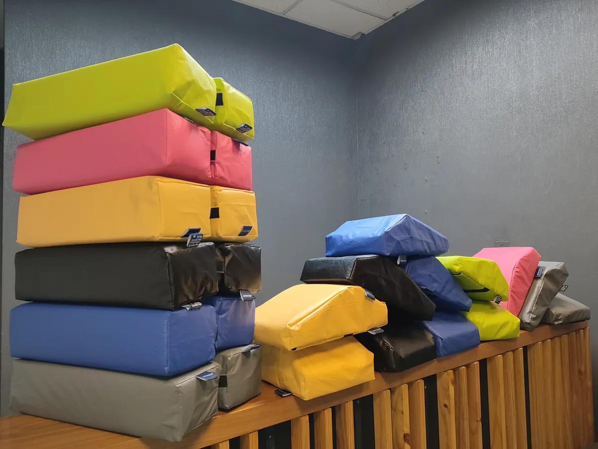 Cojines Ergoclin apilados en sus seis colores: verde lima, rosa, amarillo, negro, azul rey y gris